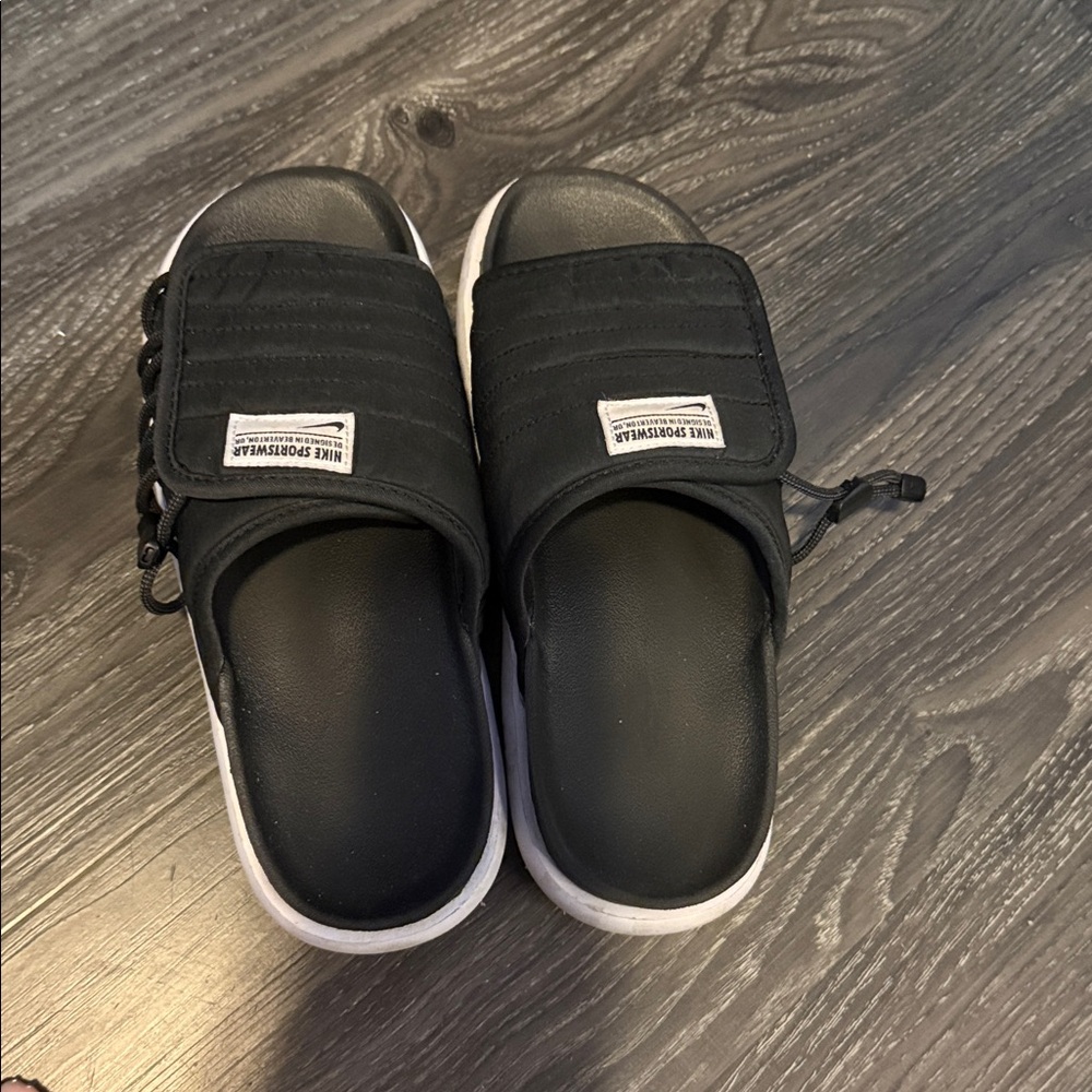 Nike sportswear worn black slides. Giving puffer jacket vibes